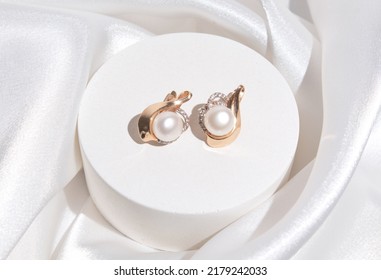Pearl earrings with golden fittings on shiny beige silk background. Beautiful accessories for women. Elegant jewelery gift or present for wedding or saint valentine's day. - Shutterstock ID 2179242033