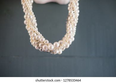 Pearl Necklace Hanging In Front Of Blue Wall