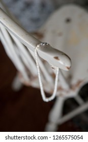 Pearl Necklace Hanging From Vintage Wooden Chair