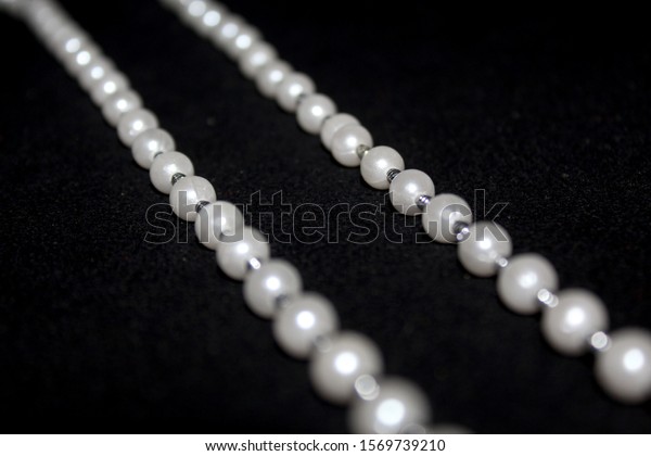 Pearl strings abstract background row\
of pearl ornaments on black background-\
Image
