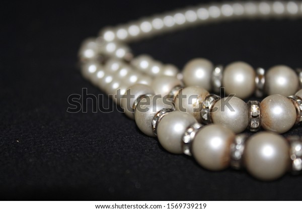 Pearl strings abstract background row
of pearl ornaments on black background-
Image