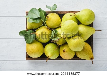 Pears. Fresh sweet organic pears with leaves in wooden box or basket on old white wooden retro table background. Autumn harvest of fruits. Top view. Food background.
