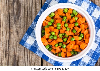 Peas And Carrots In A White Salad Bowl, View From Above On A Wooden Background. Studio Photo 
