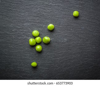 Peas of green peas on a black stone background. Fresh fruits. Harvesting. View from above.