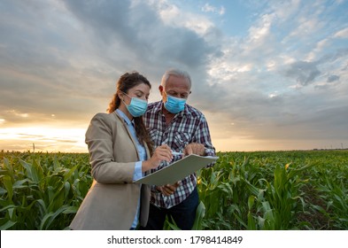 Peasant and business woman standing in corn field and looking in papers for signing documentation - Powered by Shutterstock