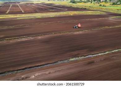 Peat Harvester Tractor On Collecting Extracting Peat. Mining And Harvesting Peatland. Area Drained Of The Mire Are Used For Peat Extraction. Drainage And Destruction Of Peat Bogs. Harvest.