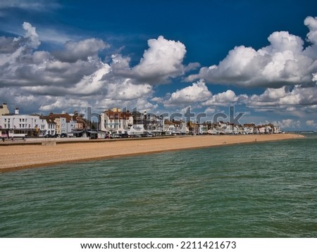 The pebble beach and seafront buildings at Deal, Kent, England, UK. Taken from the pier on a sunny day in summer with blue sky and white clouds.