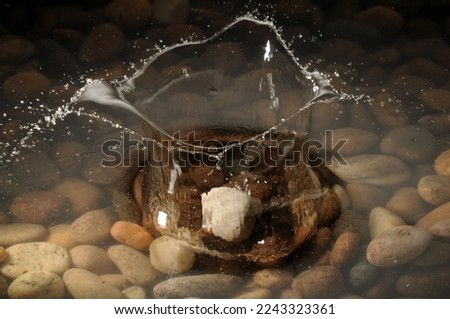 A pebble dropping into a shallow stony pool.