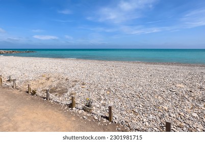 Pebble stone beach. Sea beach shore with waves in ocean. Waves in sea near coastline on empty pebble beach. Sea beach landscape. Coast pebbles. Shore landscape on Spain resort. Ocean shoreline scenic. - Powered by Shutterstock