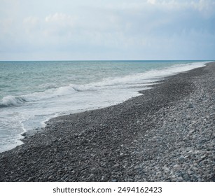 pebble stones by the sea. Silky blue waves of Black sea. Coast. Waves and round pebbles on ocean beach. Turquoise water and sea foam. - Powered by Shutterstock
