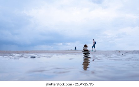 Pebble tower by seaside with blurry seascape, Stack of Zen rock stones on the sand, Stones pyramid on the beach symbolizing, stability, harmony balance with shallow depth of field.
