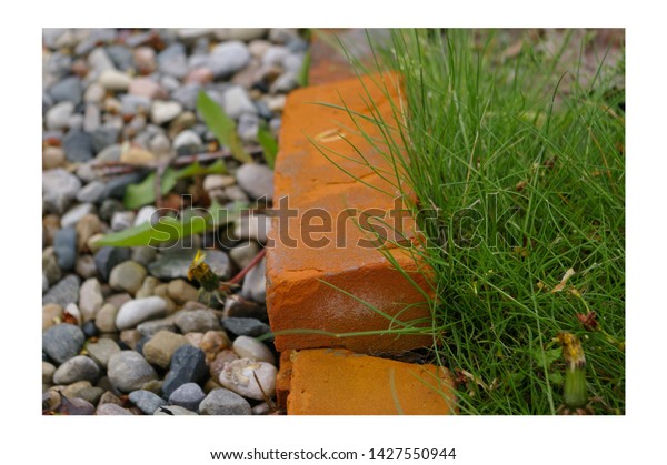 Pebbles on the left side, grass on the
right side, the middle divider being an orange
brick.