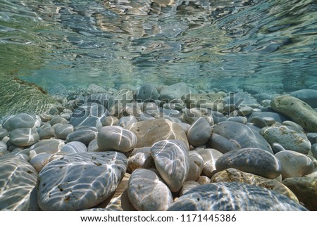 Pebbles and rocks below water surface underwater in the Mediterranean sea, Valencia, Spain