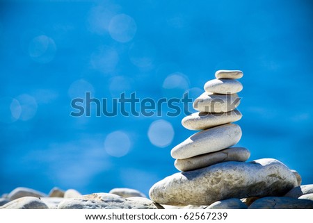 Pebbles stack balance over blue Adriatic sea in Croatia. Blue sky and water on sunny coast in summer.