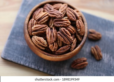 Pecan nut close-up in a round wooden cup on a black shabby board on wooden table background.Nuts and seeds. .Healthy fats.Heap shelled Pecans nut closeup.keto diet.Tasty raw organic food snack