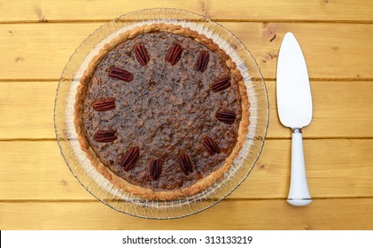 Pecan pie decorated with nuts, pie server on the table beside