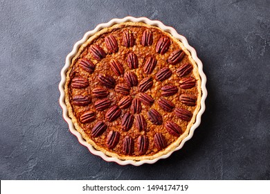 Pecan Pie, Tart In Baking Dish. Traditional Festive Thanksgiving Dessert. Dark Background. Top View.