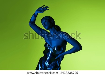 peculiar alluring woman in futuristic sci fi attire posing in blue lights on green backdrop