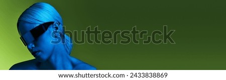 peculiar blonde woman with sci fi robotic sunglasses posing in blue lights on green backdrop, banner