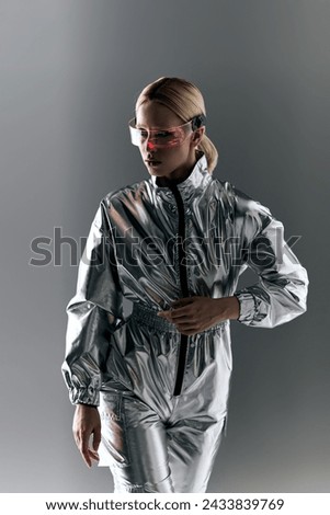 peculiar woman with futuristic glasses in silver attire doing robotic motions and looking away