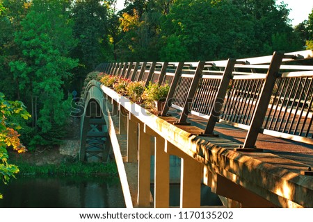 Pedestraiins bridge over the river surrounded by green trees in the evening sun light in Latvia Ogre city.