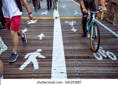 Pedestrian And Bicycle Riders Sharing The Street Lanes With Road Marking In The City. People Walking And Riding On Bicycle On City Street.