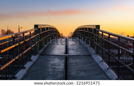 Pedestrian bridge with iron railings in the sunset sky