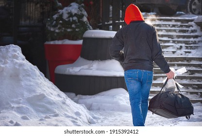 Pedestrian Courier Deliver Food Order. Delivery Man During Snowfall With Thermal Bag And Liquid Storage Container Walk Through Snowy Street To Clients. Delivery Service From Cafes And Restaurants.