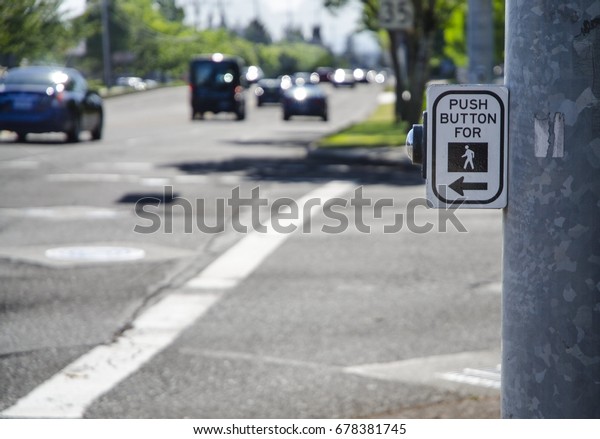 Pedestrian cross walk sign and button on busy\
street with cars and speed limit sign.  Male symbol on sign and\
sticker on steel\
pole.