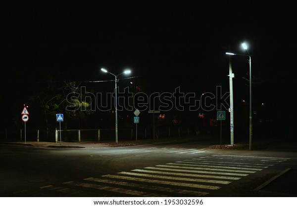 Pedestrian crossing at\
night in the illumination of street lamps in a post-Soviet city,\
devastation
