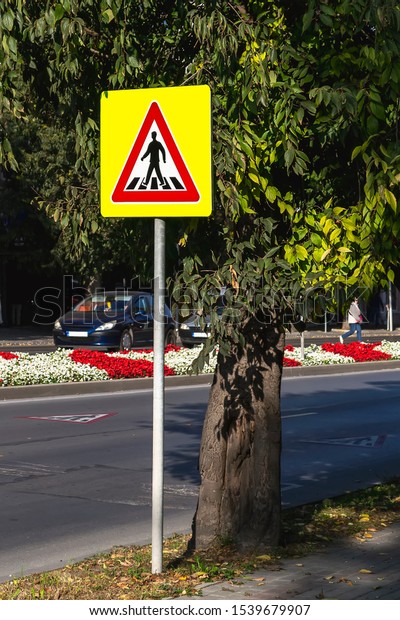 The pedestrian\
crossing sign on a bright yellow background made of a reflective\
fluorescent film for better visibility. Traffic signs and rules.\
City street during sunny day.\
