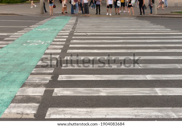 Pedestrian crosswalk across the\
road. A wide zebra crossing across the street. Crossing with bike\
paths.