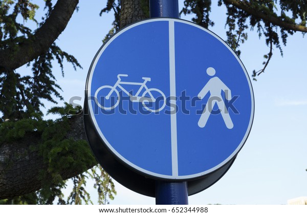 Pedestrian and cycle dividing lane sign with\
trees in background