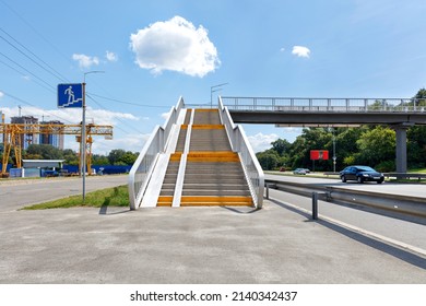 A pedestrian overpass across a busy city highway provides access from a microdistrict under construction to a green city park. ?opy space. - Shutterstock ID 2140342437