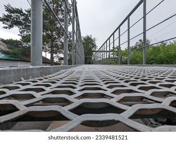 Pedestrian perforated metal bridge made of small cells with a drainage system. Photo. Selective focus. Close-up.