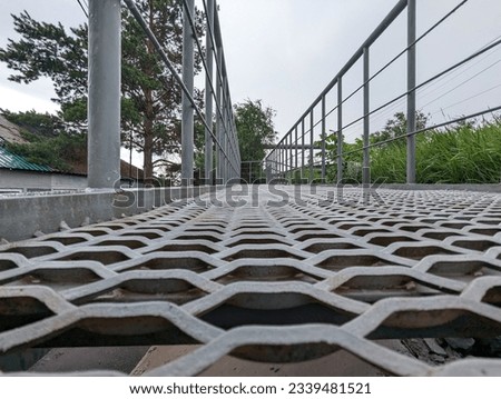 Pedestrian perforated metal bridge made of small cells with a drainage system. Photo. Selective focus. Close-up.