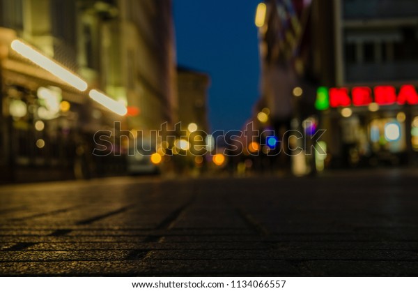 Pedestrian road in the night city with a\
bright bokeh on the background. Blurry background texture of street\
at night in urban city\
environment.