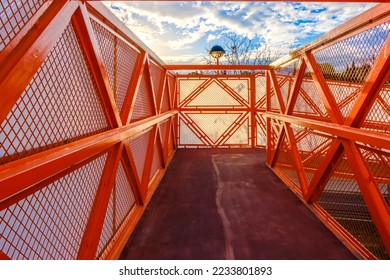 For pedestrian safety, a fenced-in metal walkway crosses over a road. - Shutterstock ID 2233801893