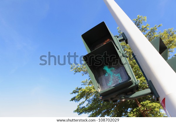 pedestrian signal (Traffic lights with the green\
light lit) with blue\
sky