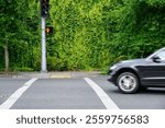 Pedestrian street crossing, crosswalk to accessible sidewalk entry, red hand LED traffic signal with car turning, against a green vine covered wall background
