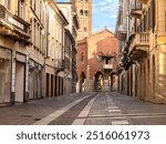 A pedestrian street with unmarked shops and no people leads to the 13th-century medieval palace known as the Arengario in the centre of Monza