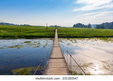 Pedestrian suspension bridge of steel and wood over the river, summer in Russia - Powered by Shutterstock