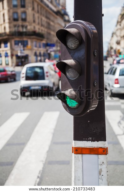 pedestrian traffic light with blurred\
people in the background at a pedestrian crossing in\
Paris