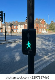 Pedestrian traffic light control button at crosswalk showcasing green person to indicate to pedestrians that it is safe to cross the road at zebra crossing. Pedestrian safety in the big city of London