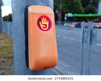 Pedestrian Traffic Light Push Button with Red Don't Walk Hand Signal. Close-up of orange pedestrian crossing button showing illuminated red hand 