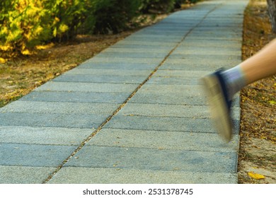 Pedestrian walking path with perspective stretching into distance, One leg of running white man washed out due to movement as he strays from straight path into unknown territory outside road.