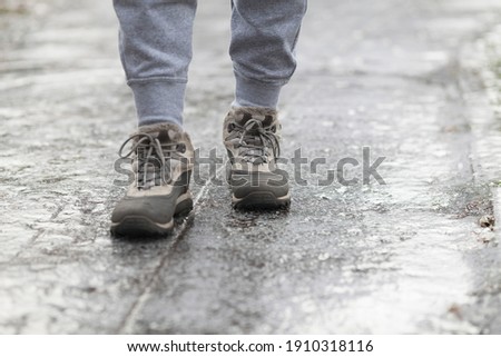A pedestrian walks along a dangerous icy sidewalk. Frozen rain.