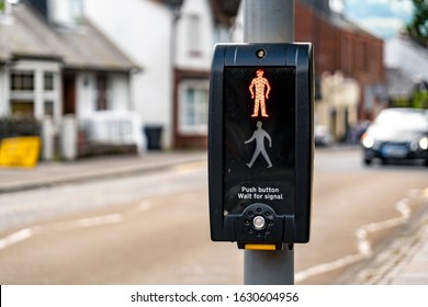 Pedestrian Zebra Crossing With An English Text Telling People To Wait For Appropriate Signal And Push The Button. The Blurred Car In The Background Is Approaching 