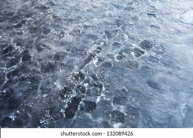 Pedestrians Footprints In Blue Road Ice. Street Sleet Background