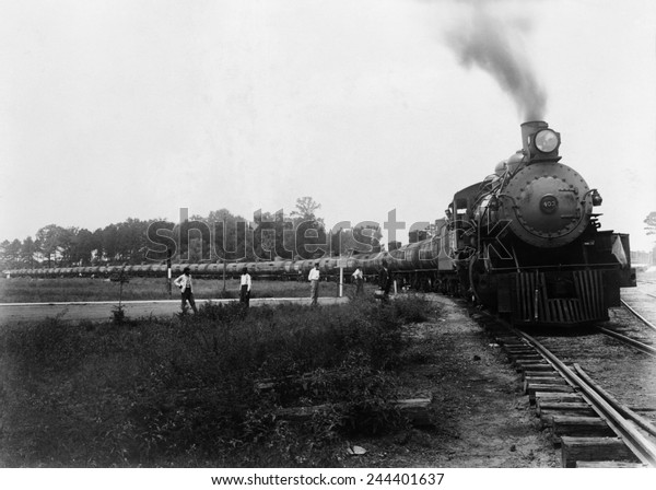 Pedestrians waiting at a railroad\
crossing for Louisiana Arkansas Railroad train pulling tank cars to\
pass. Ca. 1920-1940.\
LC-USZ62-106094